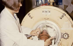 Instructional slide of a staff member being put into the iron lung